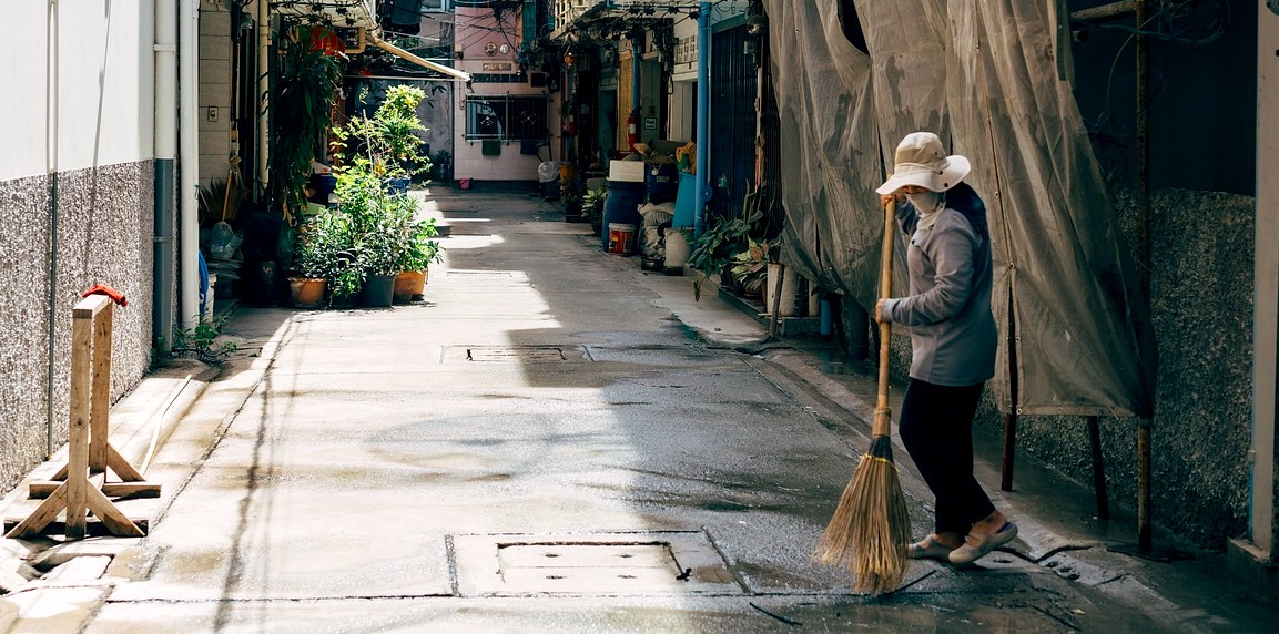 mulher gari varre rua em bairro pobre da cidade